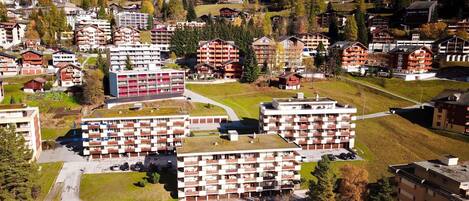 A cluster of multi-story buildings with balconies, surrounded by a mountainous landscape.