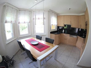 A compact kitchen with a dining table, chairs, and a microwave. - Edelweiss C 31 # 4-bed apartment, Dusche, WC 4-Bettwohnung, Dusche, WC by Interhome (Leukerbad)