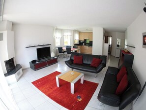 A modern living room with a flat-screen TV, a black leather sofa, a wooden coffee table, and a red rug. - Edelweiss C 31 # 4-bed apartment, Dusche, WC 4-Bettwohnung, Dusche, WC by Interhome (Leukerbad)