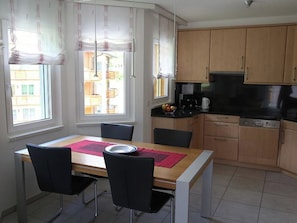 A dining area with a table, chairs, and a view of buildings outside. - Edelweiss C 31 # 4-bed apartment, Dusche, WC 4-Bettwohnung, Dusche, WC by Interhome (Leukerbad)