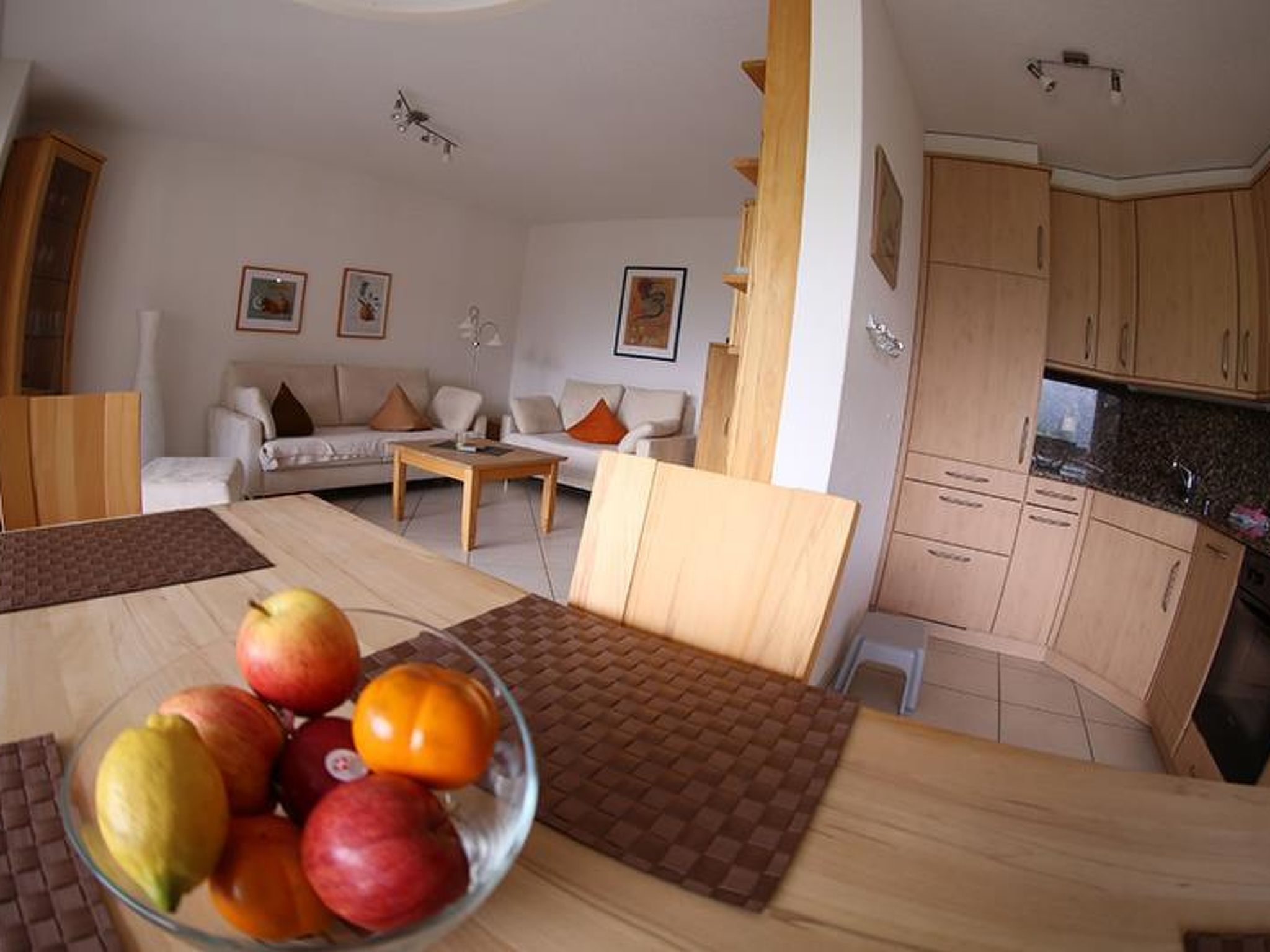 A modern living room with a sofa, coffee table, and a dining area with a table set for a meal.