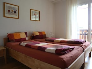 Ein Hotelzimmer mit zwei Betten, jedes mit einer anderen Bettdecke, einem Nachttisch und einem Fenster mit Vorhängen.