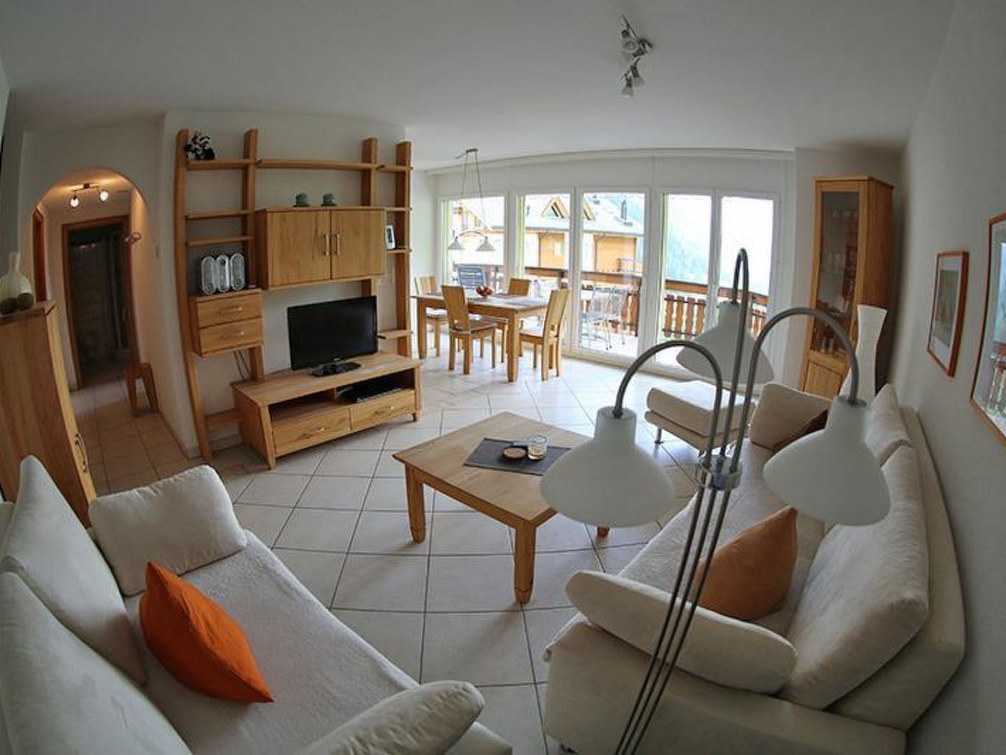 En stue med sofa, sofabord, fjernsyn og et spiseområde med stole og bord.