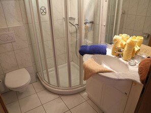 Ein Badezimmer mit Toilette, einer gläsernen Duschkabine und einem Waschbecken mit Handtüchern.