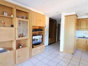 Ein geräumiger Wohnbereich mit Holzausstattung, einem Fernseher und einer Küchenzeile.