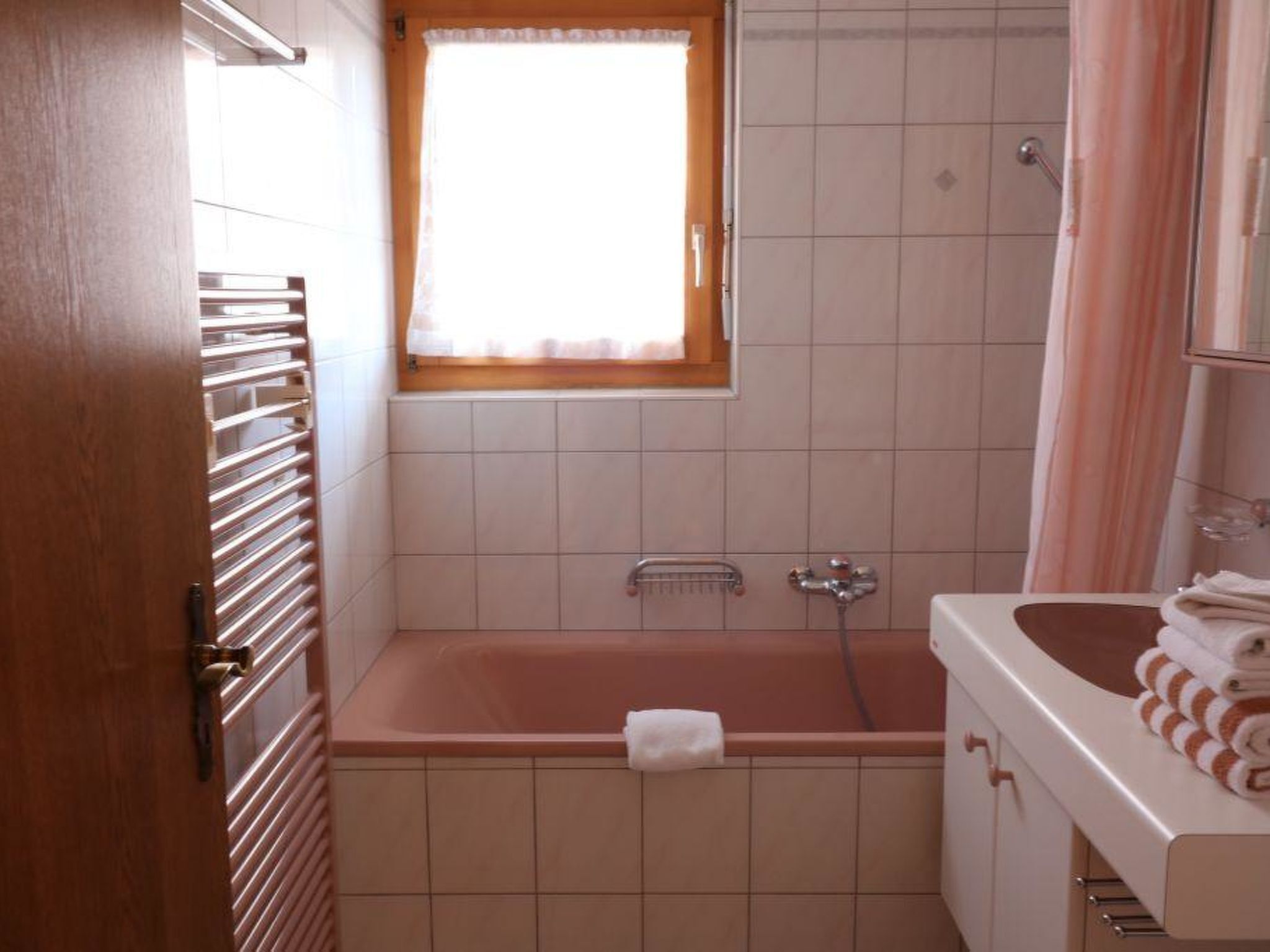 Une salle de bain avec une baignoire, une fenêtre, une douche et un lavabo, ainsi que des serviettes.