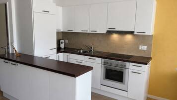 A modern kitchen with white cabinetry, a built-in oven, and a stainless steel sink.