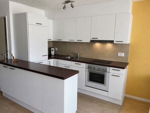 Eine moderne Küche mit weißen Schränken, einem eingebauten Backofen und einer Edelstahl-Spüle.
