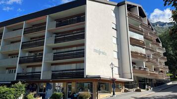 A multi-story building with balconies, a sign reading 'majesta,' and a street in front.