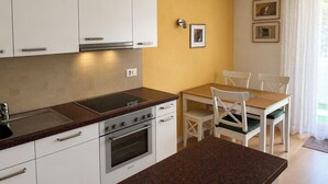 Una cucina moderna con mobili bianchi, un piano di lavoro in granito e un'area pranzo con tavolo in legno e sedie bianche.