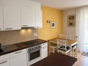 Eine moderne Küche mit weißen Schränken, einer Granitarbeitsplatte und einem Essbereich mit einem Holztisch und weißen Stühlen.