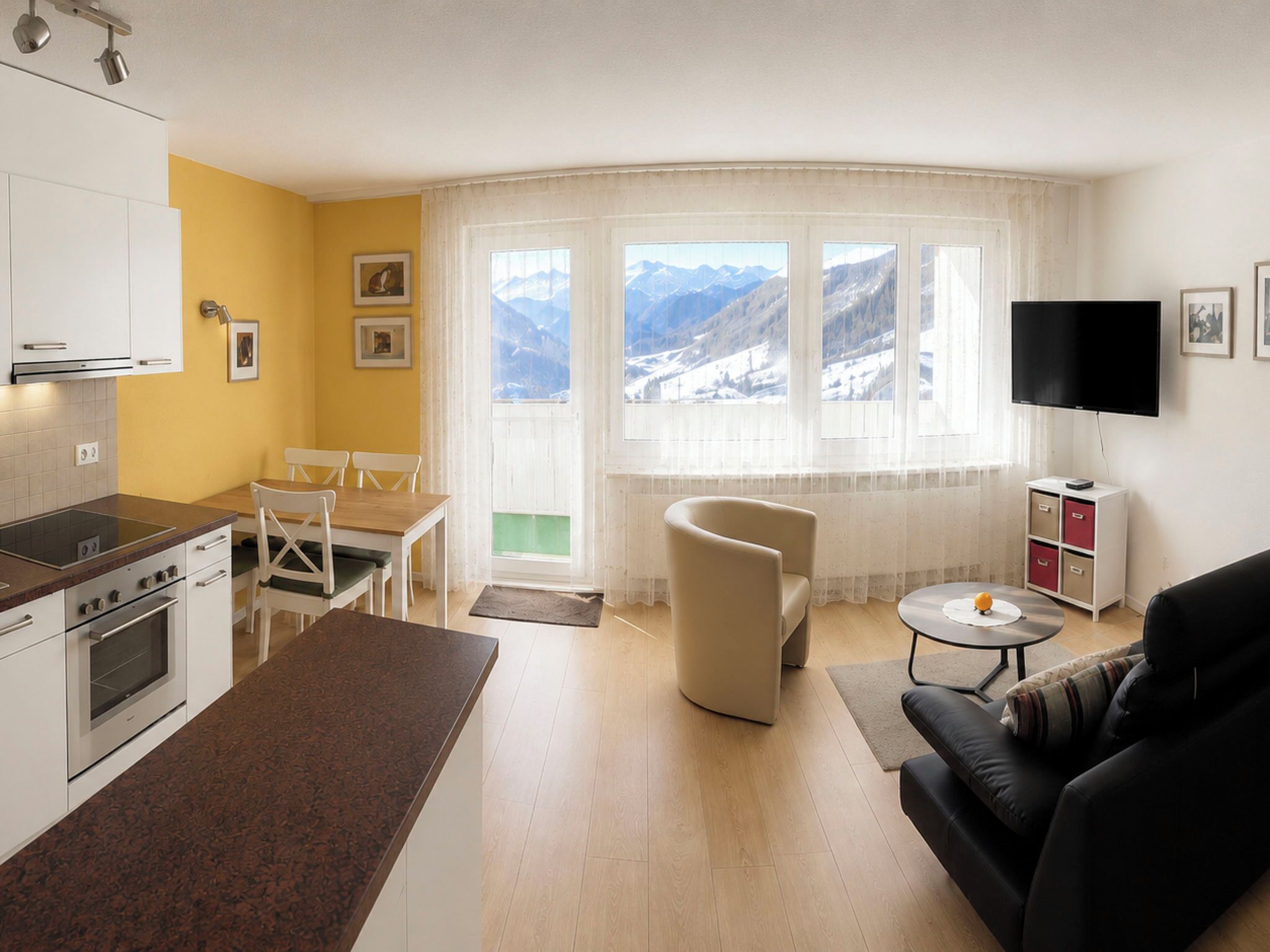 Eine moderne Küche mit weißen Schränken und einem Essbereich mit Tisch und Stühlen.