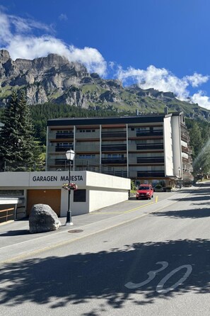 Ein Gebäude mit der Aufschrift 'GARAGEN MAISTETA', einem Parkplatz und einem roten Auto davor.