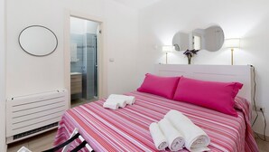 A hotel room with a bed, two pillows, a round mirror, a bedside lamp, and a radiator.