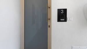 A door with a frosted glass panel, a wall-mounted number plate labeled '3', and a light switch.