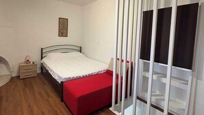 Un dormitorio con cama, mesita de noche, armario y luz en el techo.