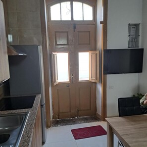 Eine Küche mit Doppeltüren, einem Kühlschrank, einer Spüle und einem Essbereich mit Tisch und Stuhl.