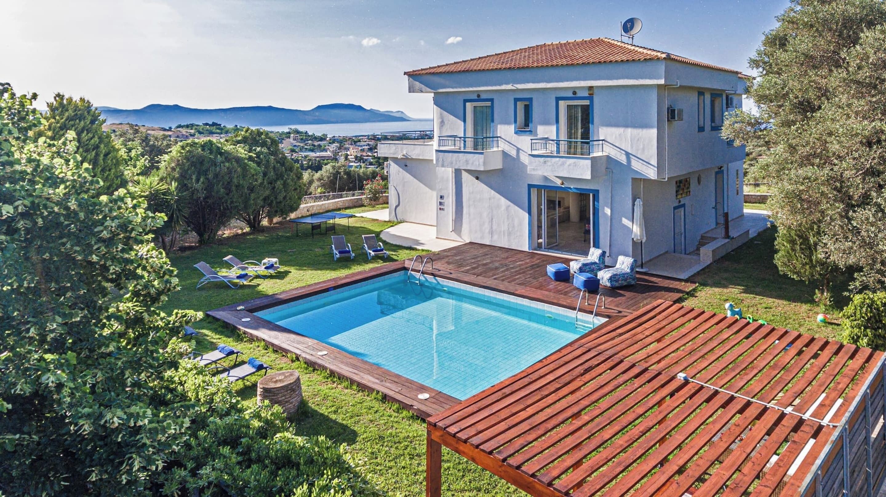 A two-story building with a swimming pool, outdoor seating, and a view of the landscape.