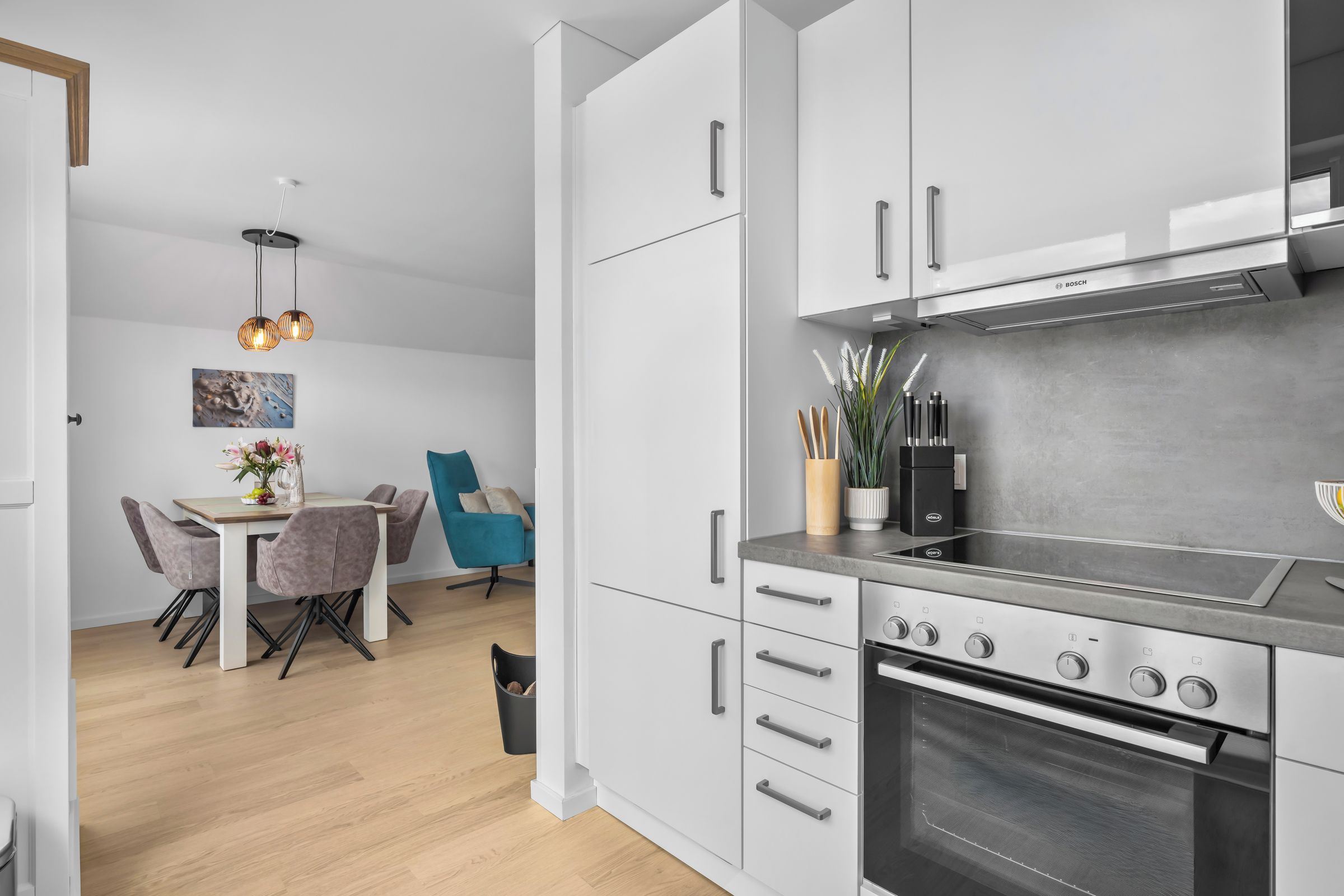Een moderne keuken met witte kasten, een Bosch afzuigkap en een inbouwoven.