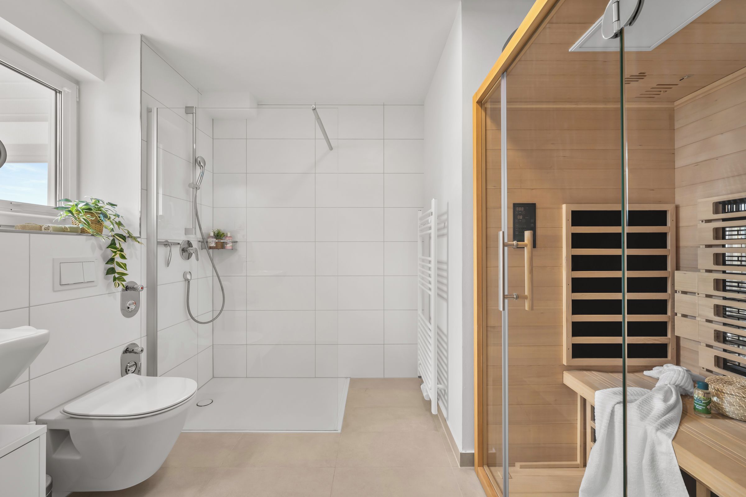 Une salle de bain moderne équipée de toilettes, d’une douche et d’un sauna en bois.