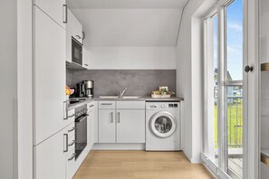 Eine moderne Küche mit Einbauofen, Mikrowelle, Kaffeemaschine und Waschmaschine.