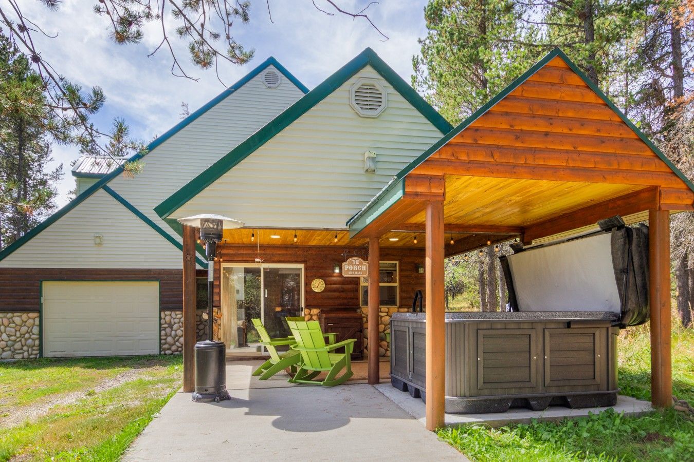 A lodge with a covered patio, outdoor seating, and a hot tub.