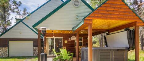 A lodge with a covered patio, outdoor seating, and a hot tub.