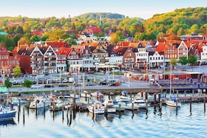 Ein Yachthafen mit angestaubten Booten, umgeben von traditionellen Gebäuden im europäischen Stil mit roten Dächern und weißen Fassaden.