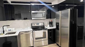 A modern kitchen with stainless steel appliances, a microwave, oven, and refrigerator. - Room-magnificent Brand New Luxurious Bas (Edmonton)
