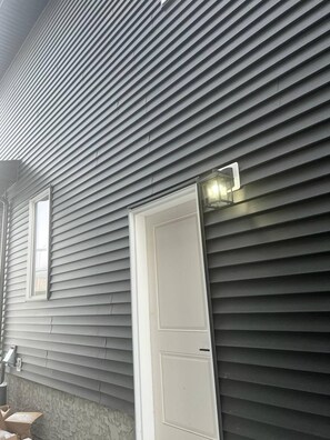 Um edifício com revestimento horizontal, uma porta branca e uma pequena janela.