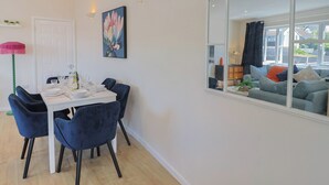 A dining area with a white table set for four, blue chairs, a pink lamp, and a painting on the wall. - 2 Mill Green Court (Lyme Regis)