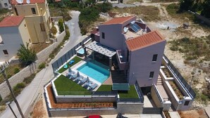 Un edificio moderno con piscina, un'auto rossa e un piccolo giardino.