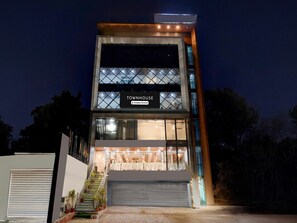 Ein modernes Reihenhaus mit einem gut sichtbaren Schild mit der Aufschrift 'TOWNHOUSE', einer Garage und einer Treppe, die zum Eingang führt.
