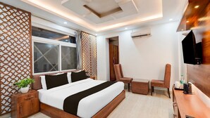 A modern hotel room with a large bed, a desk, a chair, a TV, and a window. - Townhouse Rispana Pul Haridwar (Dehradun)