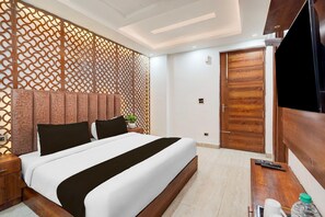 Ein modernes Hotelzimmer mit einem großen Bett, einem Holzkopfende, einem Fernseher und einer Holztür.