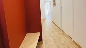 A hallway with a red wall, a wooden bench, and a white door at the end. - House with a renovated courtyard—"Le Cocon d'Albi"—5 minutes from downtown (Albi)
