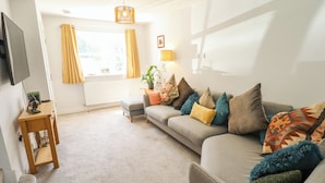 A living room with a sofa, a TV, a lamp, and a window with curtains. - Burton Fields (Driffield)