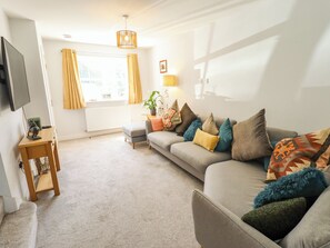 A living room with a sofa, a TV, a lamp, and a window with curtains. - Burton Fields (Driffield)