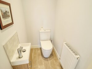 A small bathroom with a toilet, sink, and radiator. - Burton Fields (Driffield)