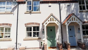 A two-story building with a red-tiled roof, white exterior walls, and a green door. - Burton Fields (Driffield)