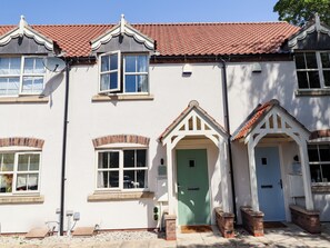 A two-story building with a red-tiled roof, white exterior walls, and a green door. - Burton Fields (Driffield)