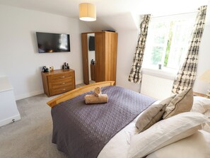 A bedroom with a bed, a wooden wardrobe, a mirror, a television, and a window with curtains. - Burton Fields (Driffield)