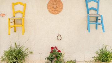 A wall with two chairs, a decorative sun, and potted plants.
