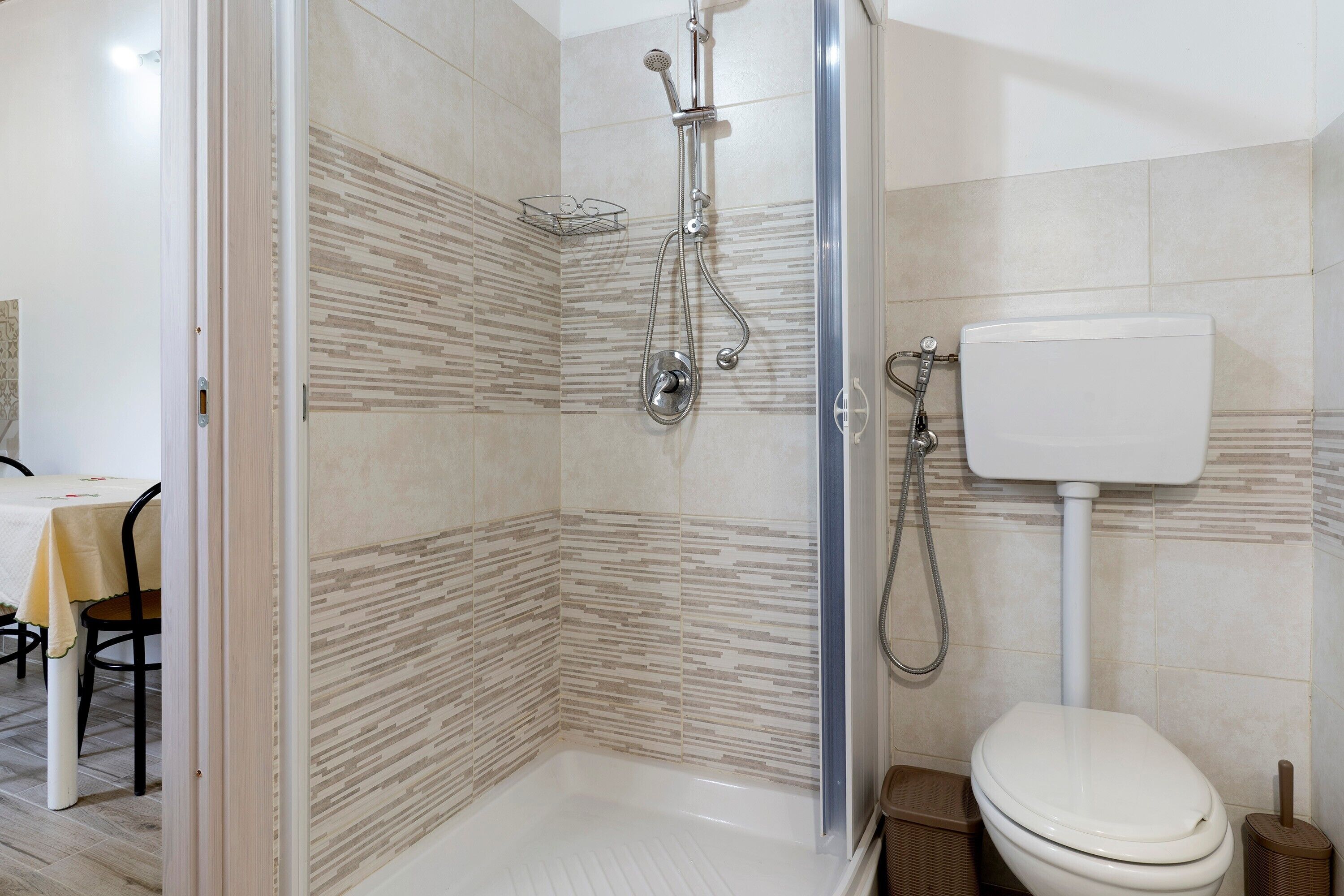 Un bagno con doccia, WC e un piccolo tavolo con sedie.