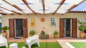 A patio area with a covered seating area, potted plants, and a wall with decorative elements. - NEW LIFE Villalba Resort - Room '101' with Shared Terrace, Wi-Fi and Air Conditioning (Villalba)