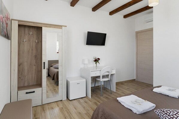 A bedroom with a bed, a desk, a chair, a TV, and a wardrobe.
