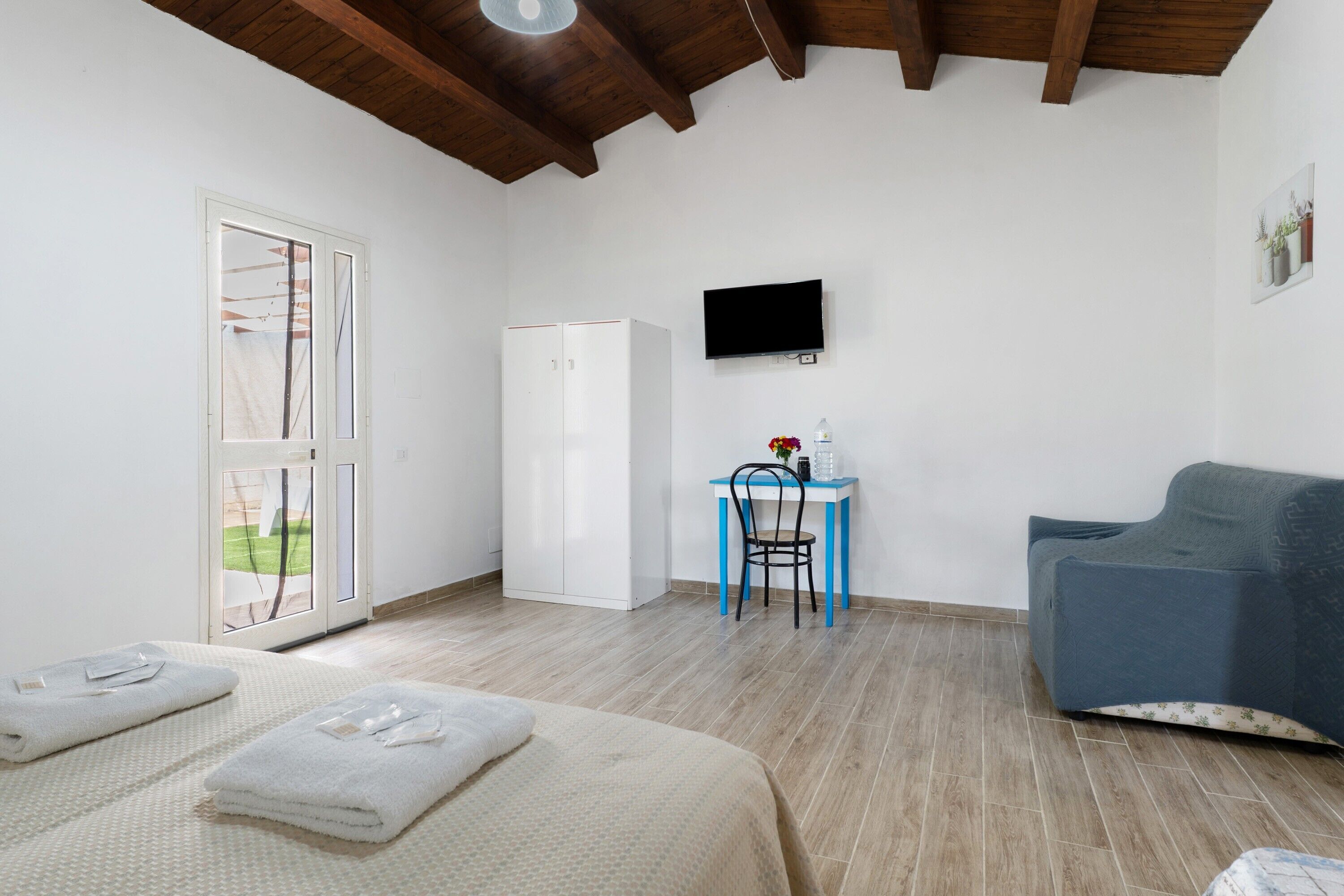Una habitación con cama, escritorio y silla, televisor y sofá.