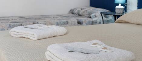 A neatly made bed with folded towels and a bedside table with a lamp.
