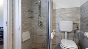 A bathroom with a shower, toilet, and a glass door leading to another room.