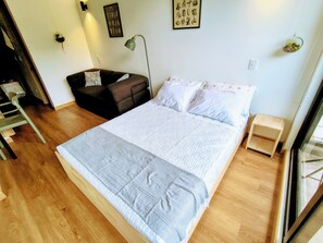 Una camera da letto con un letto, una sedia, una scrivania, una lampada e un piccolo tavolino.